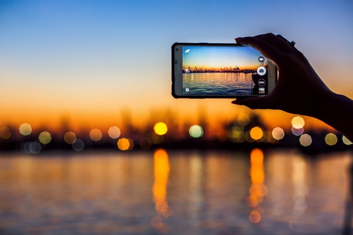 Someone taking a photo of a sunset over water