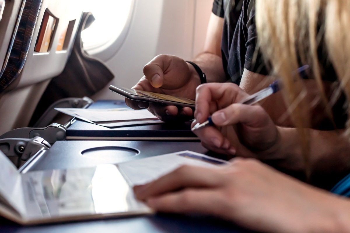 People filling out forms on an airplane tray table