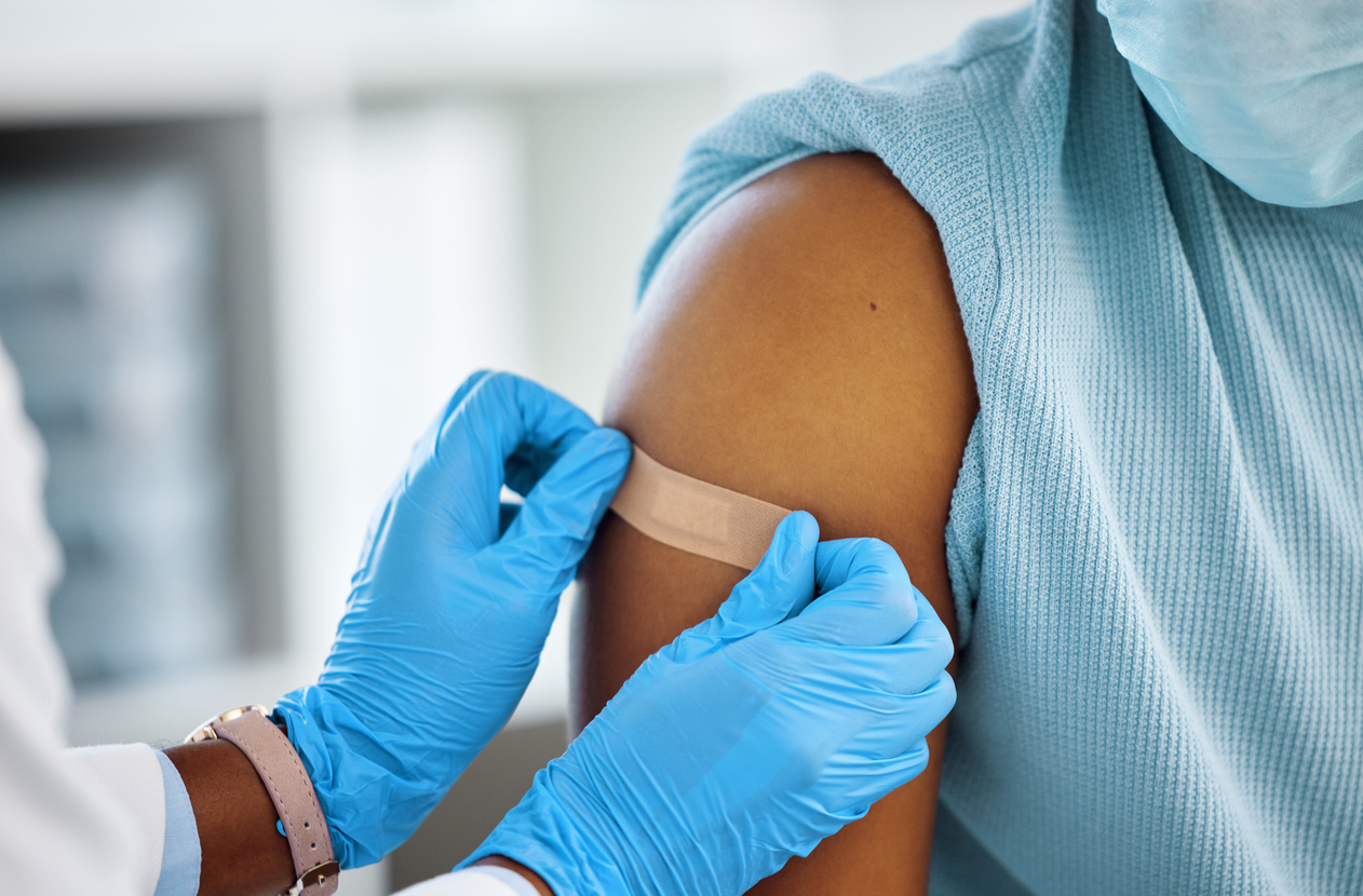 Doctor applying bandaid after vaccine shot.