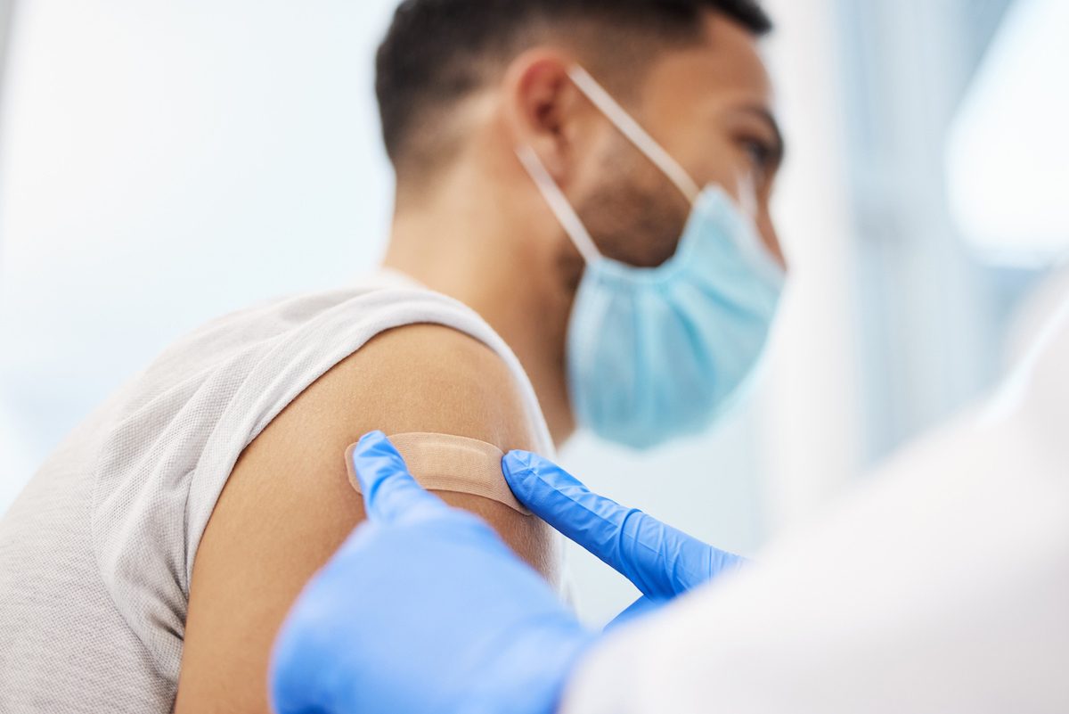 Shot of an unrecognizable doctor putting a band-aid on her patient after giving him the Covid vaccine