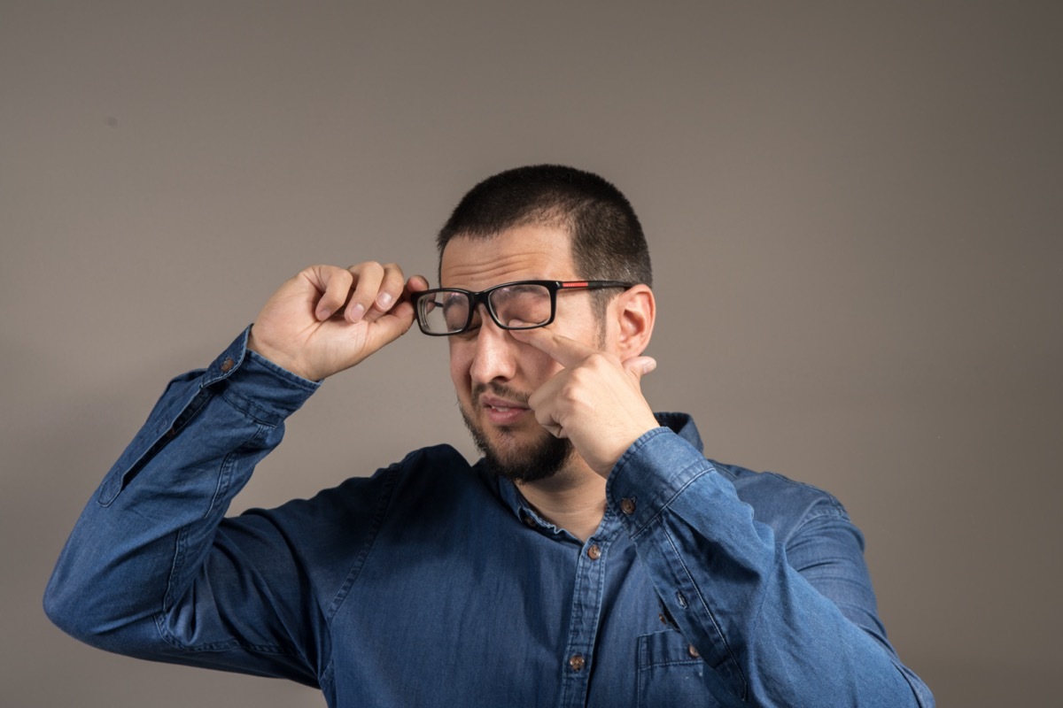 a gentleman with a beard scratching his eyes with glasses