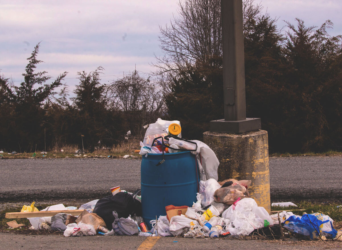 Trash overflowing out of garbage bin in parking lot