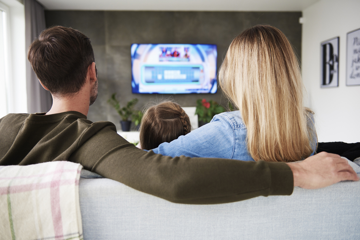 A family sitting on a couch while watching a streaming TV service