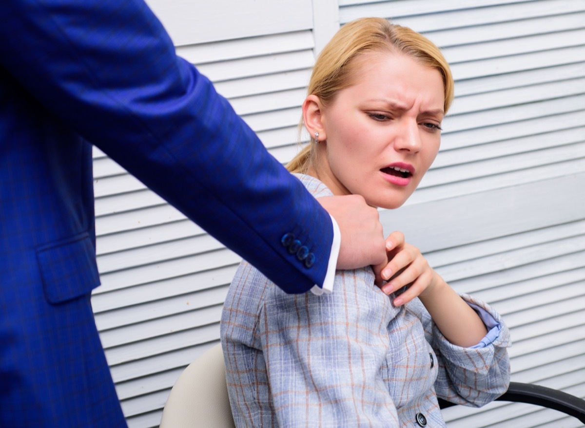 woman cringing at man's hand on her shoulder