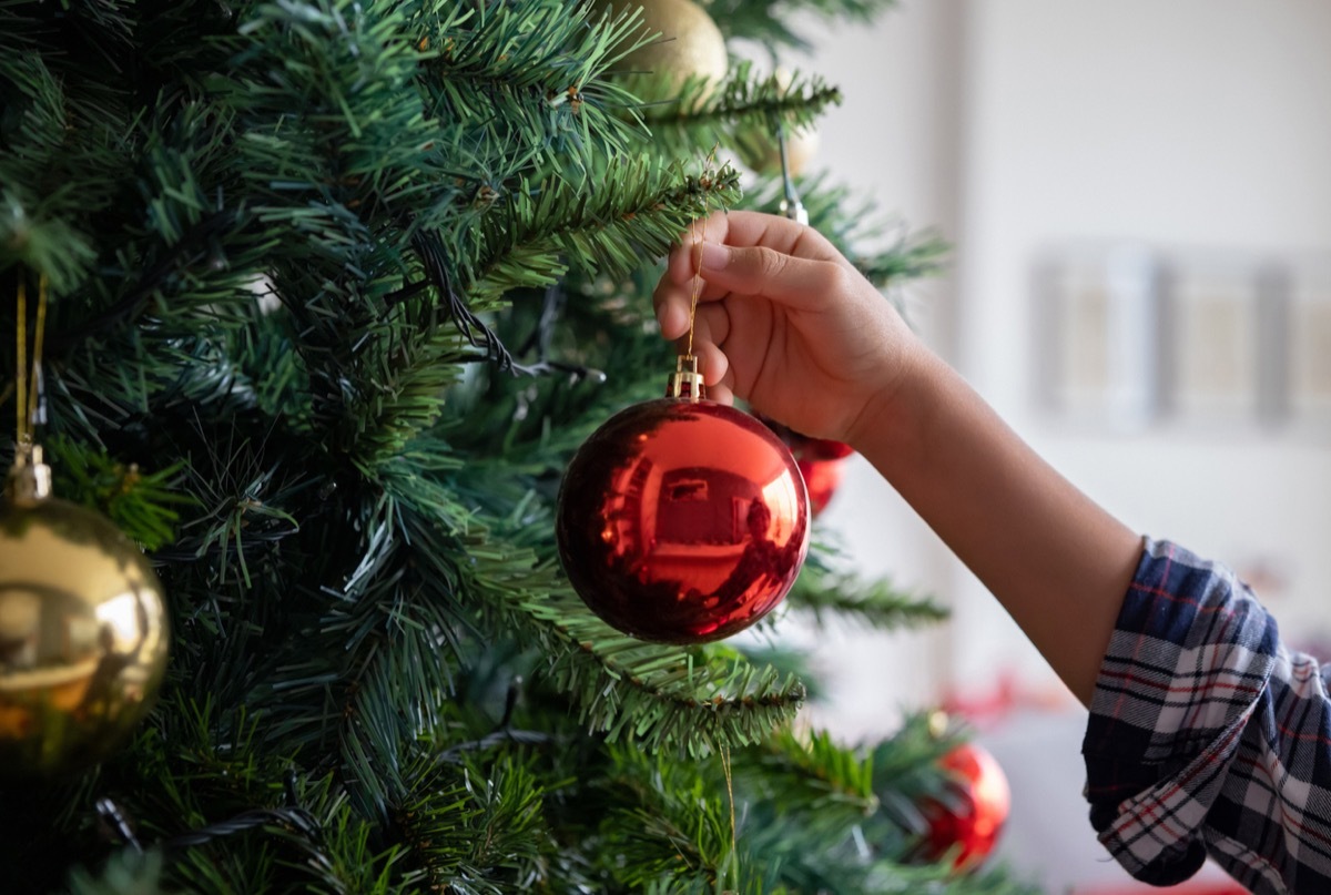 close-up of someone hanging an ornament on a christmas tree