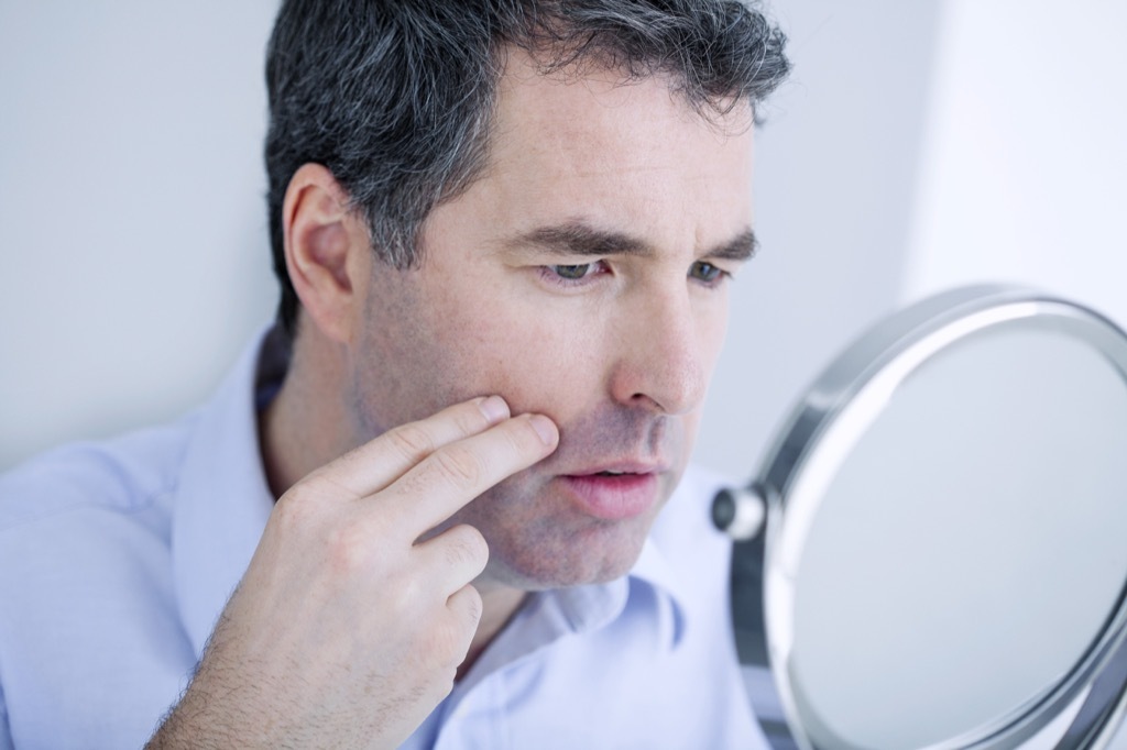 Man Looking at His Skin Symptoms of Cancer