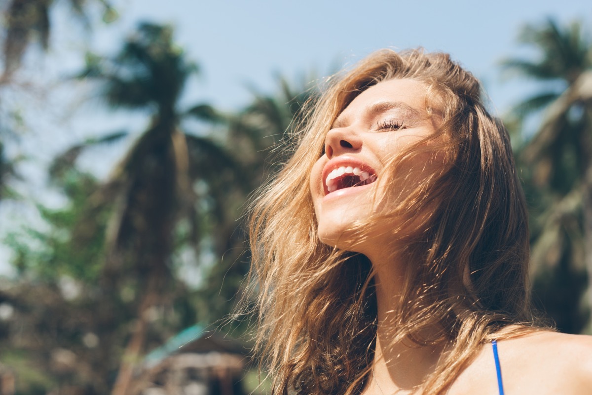 woman smiling in the sunshine while repeating positive affirmations