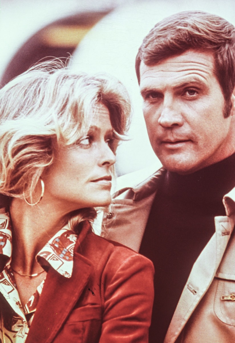 Farrah Fawcett wears a red jacket and Lee Majors wears a beige jacket and black shirt