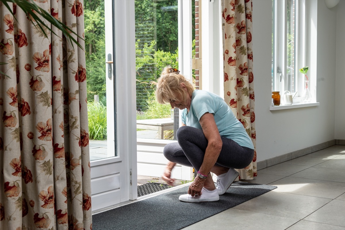 Getting fit concept. Senior woman lacing up new shoes before running.