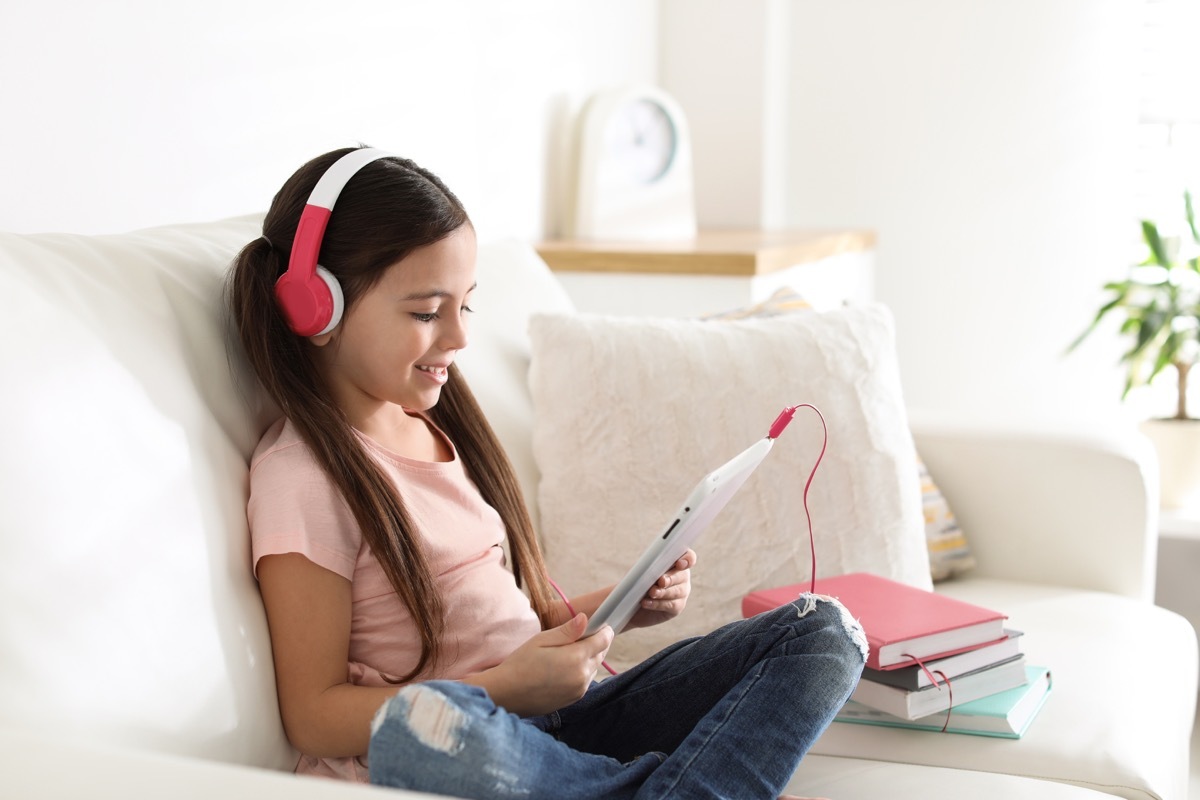 Girl on IPad with books next to her