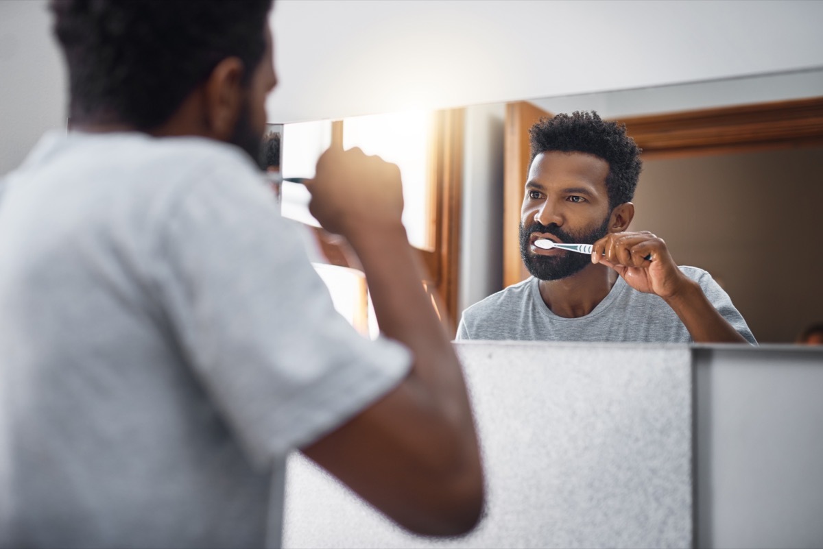 Cropped shot of a handsome young man brushing his teeth in the bathroom at home