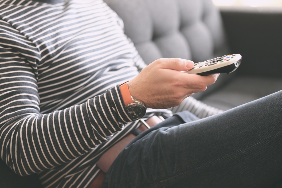 Young man holding a tv cable remote control, watching tv. Life style, entertainment, young people. fashion, design and interior concept. Natural light