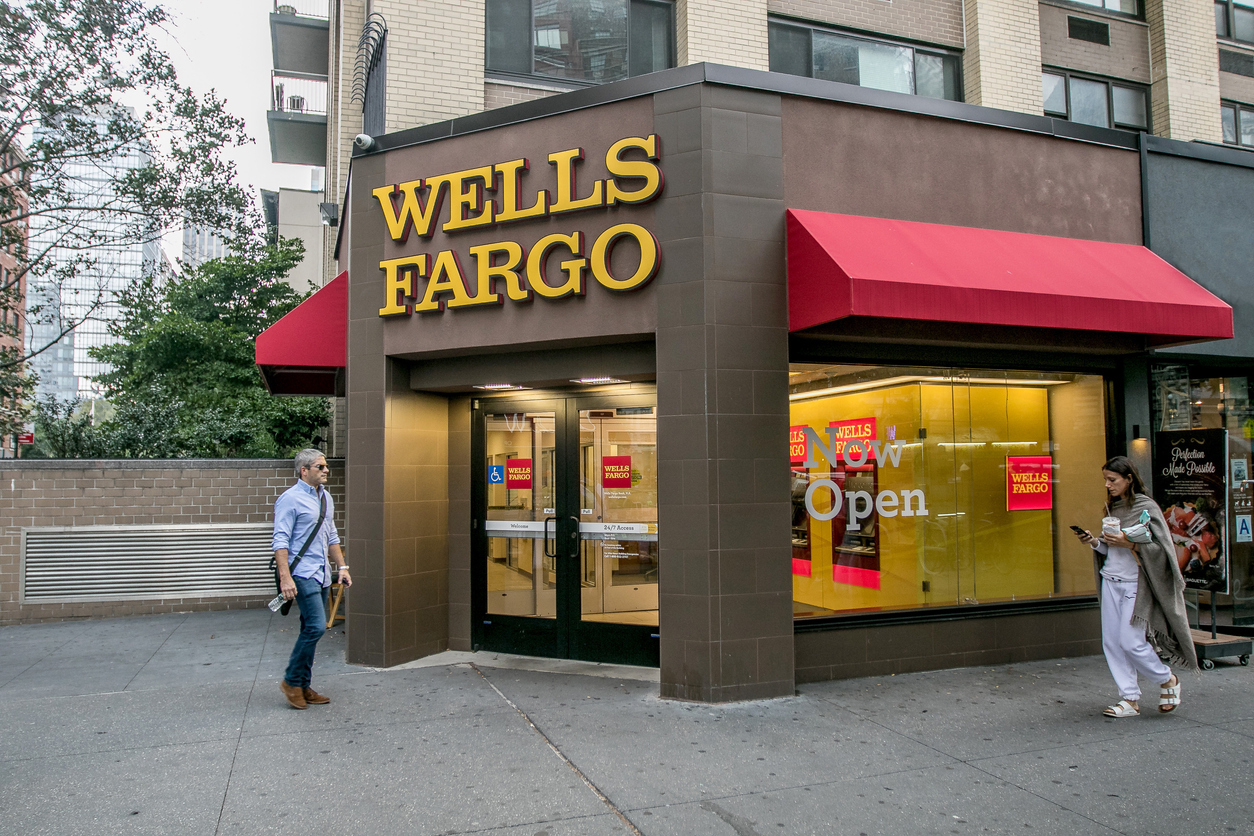 The exterior of a Wells Fargo branch with people walking by