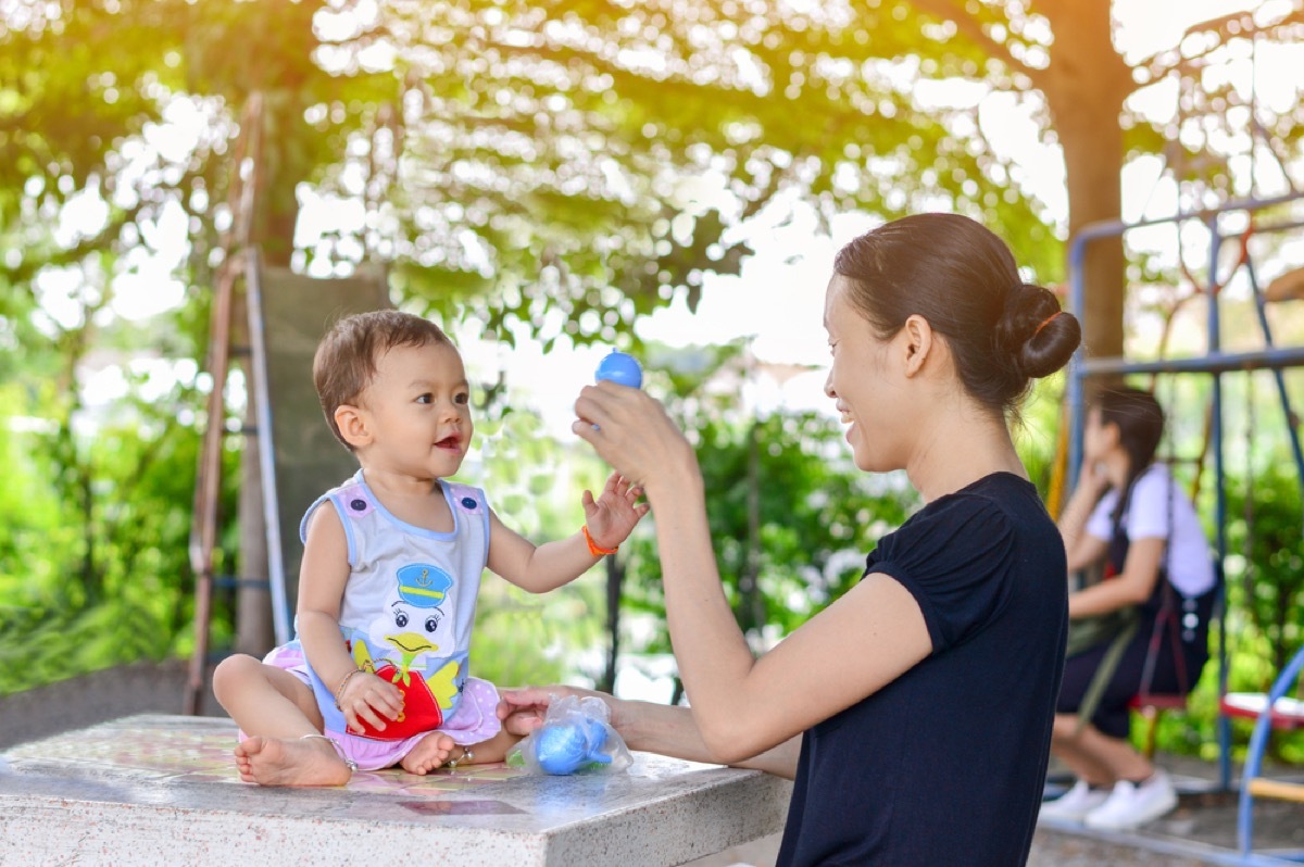 mom entertaining child with toy, parenting tips