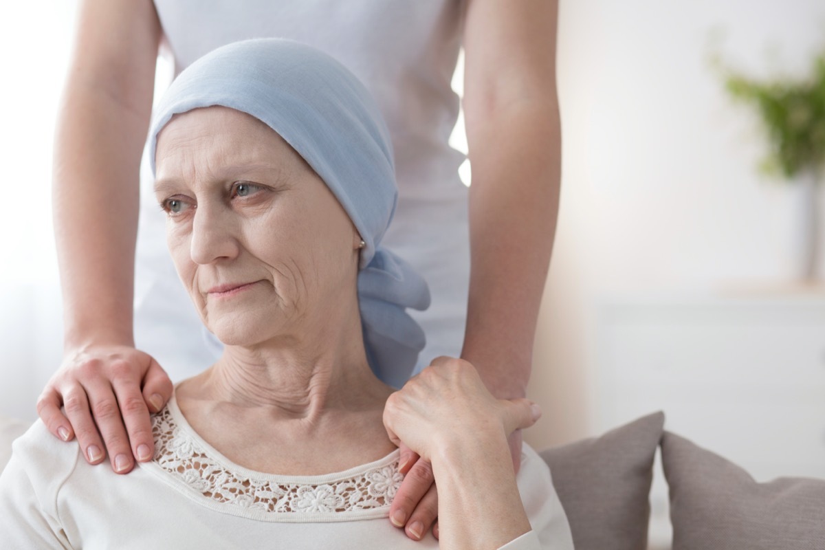 Crying elderly woman with cancer and a volunteer taking care of her