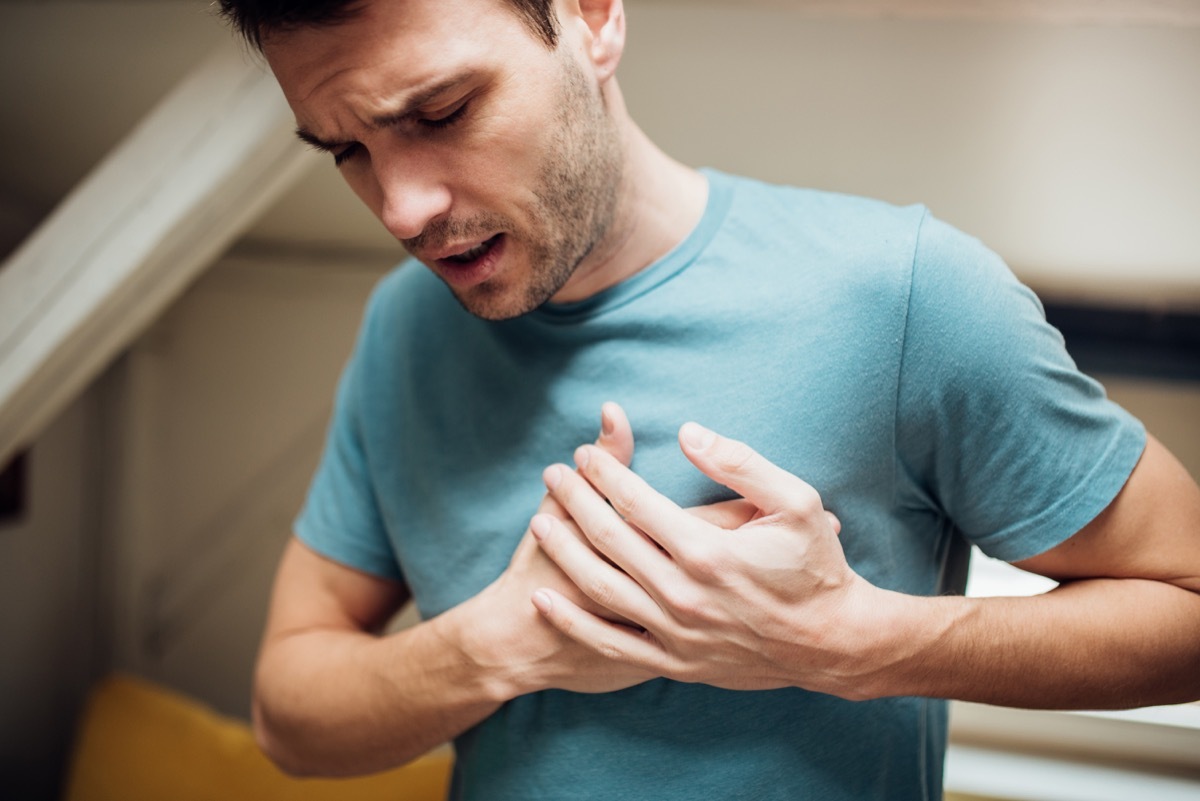 Young man holding his chest in pain