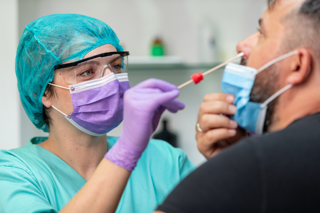 A female nurse conducts a nasal swab on a young man for a coronavirus test and contact tracing