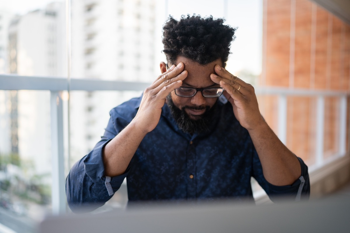 Worried man working with headache at home