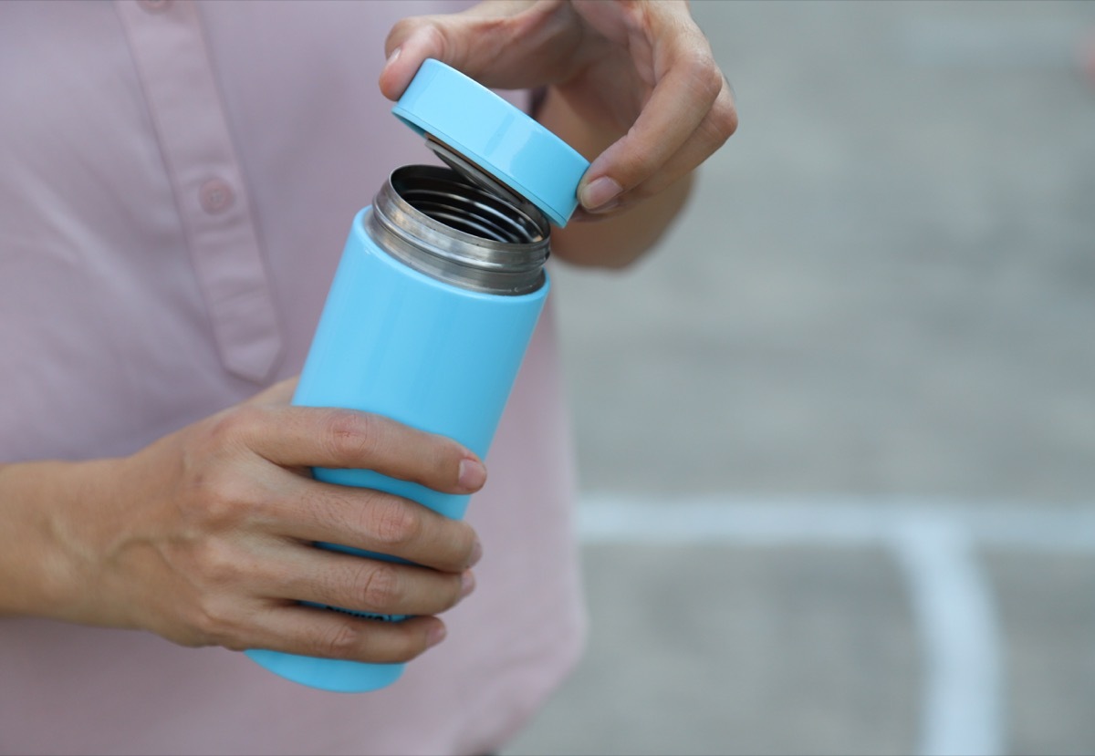 Asian woman opens water bottle, which is gross and should be cleaned daily