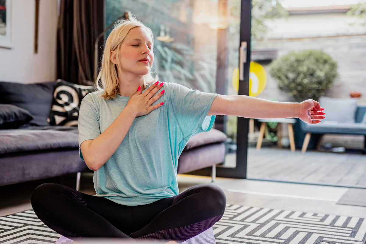 Young woman at home stretching her arm