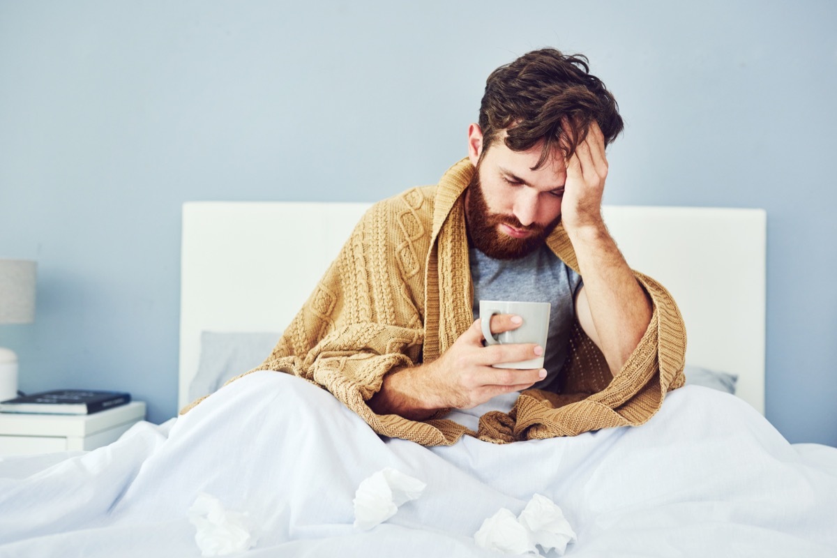 sick man sits in bed with tea