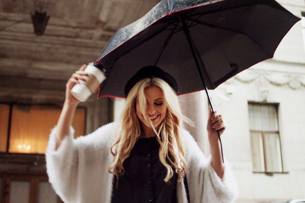 woman holding an umbrella and coffee