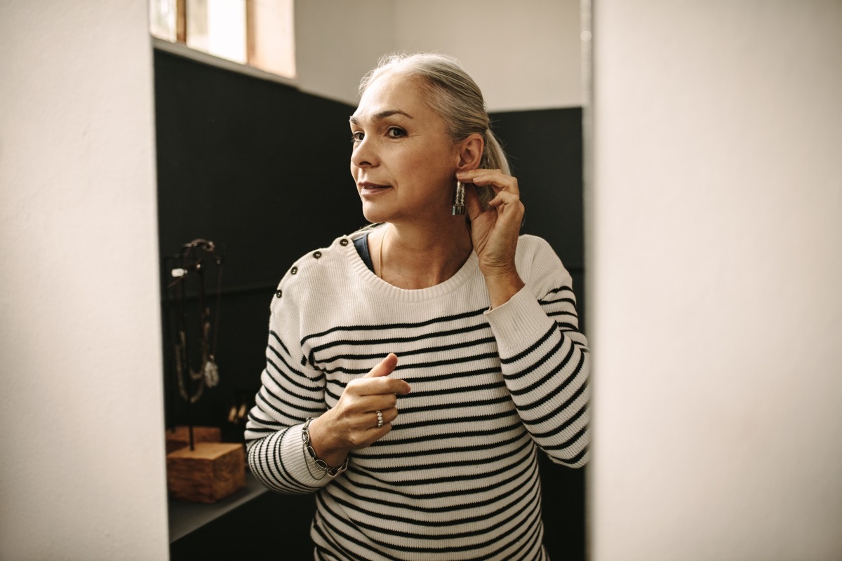 older woman putting earrings in