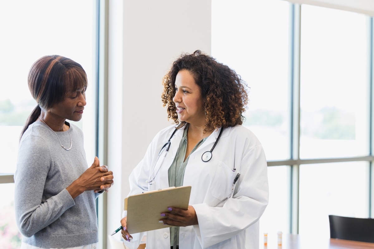 The female senior adult patient listens as the mid adult female doctor reviews the test results on the clipboard.