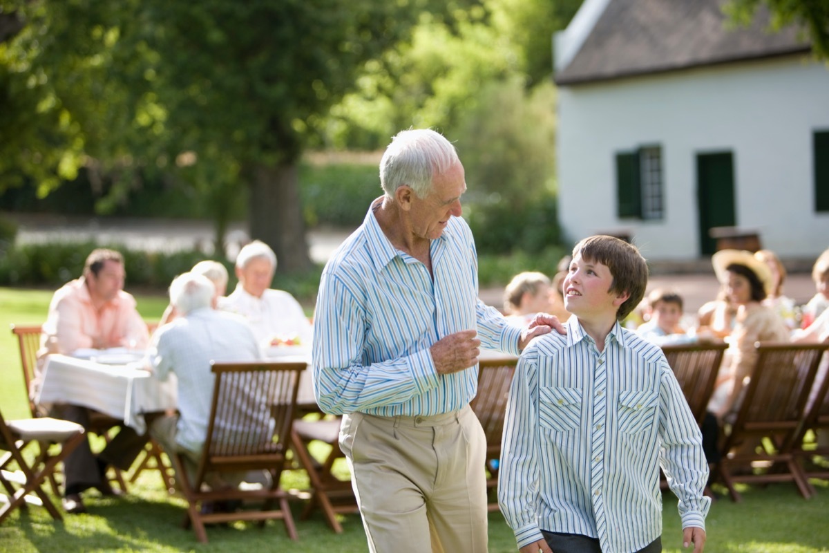 A grandfather having a conversation with his grandson at a party