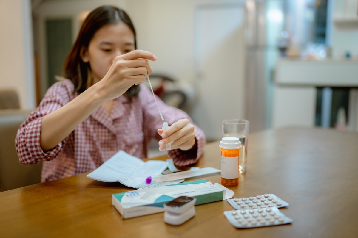 woman drops swab in a protective plastic tube after nasal swab test to check for virus at home.