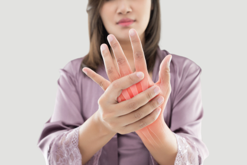 Asian woman suffering from pain in bone against gray background