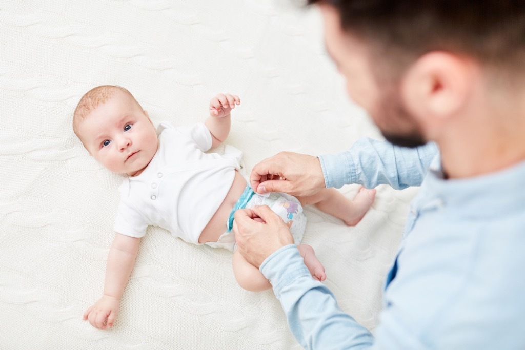 man changing baby diaper