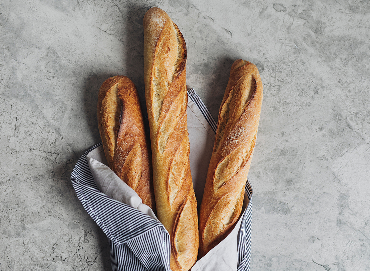 three baguette loaves on marble table with dish cloth