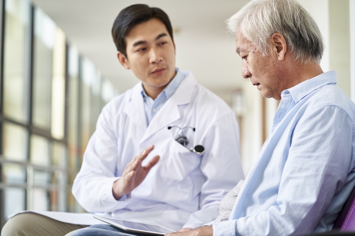 doctor talking and explaining test result and diagnosis to demoralized elderly patient in hospital hallway