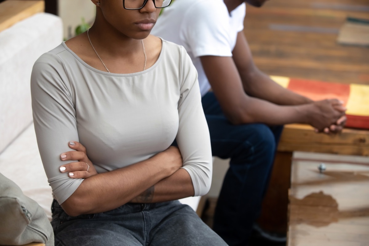 man and woman sitting on couch, facing away from each other