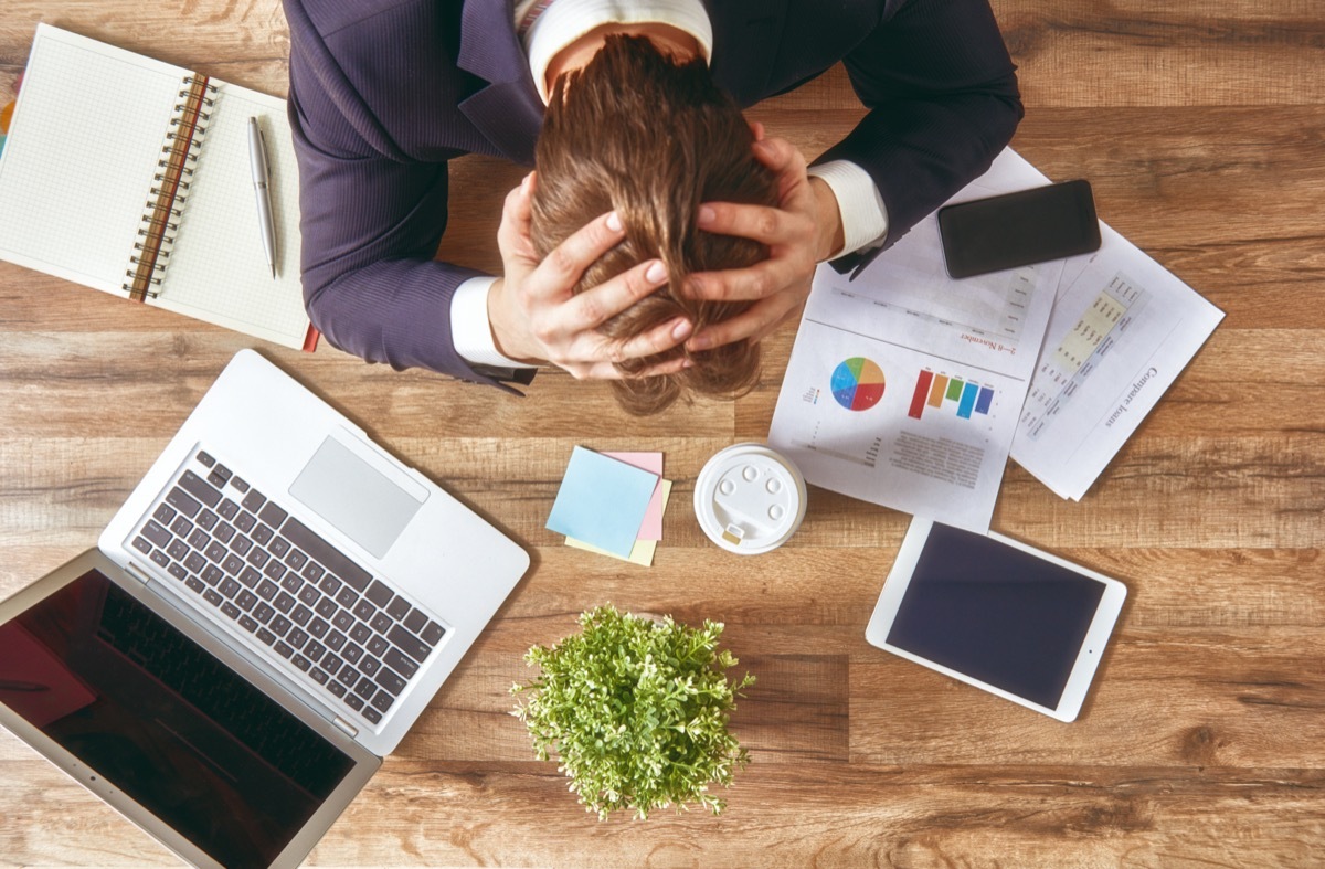 businessman in panic. a young man sits at his Desk and holds his hands on his head.