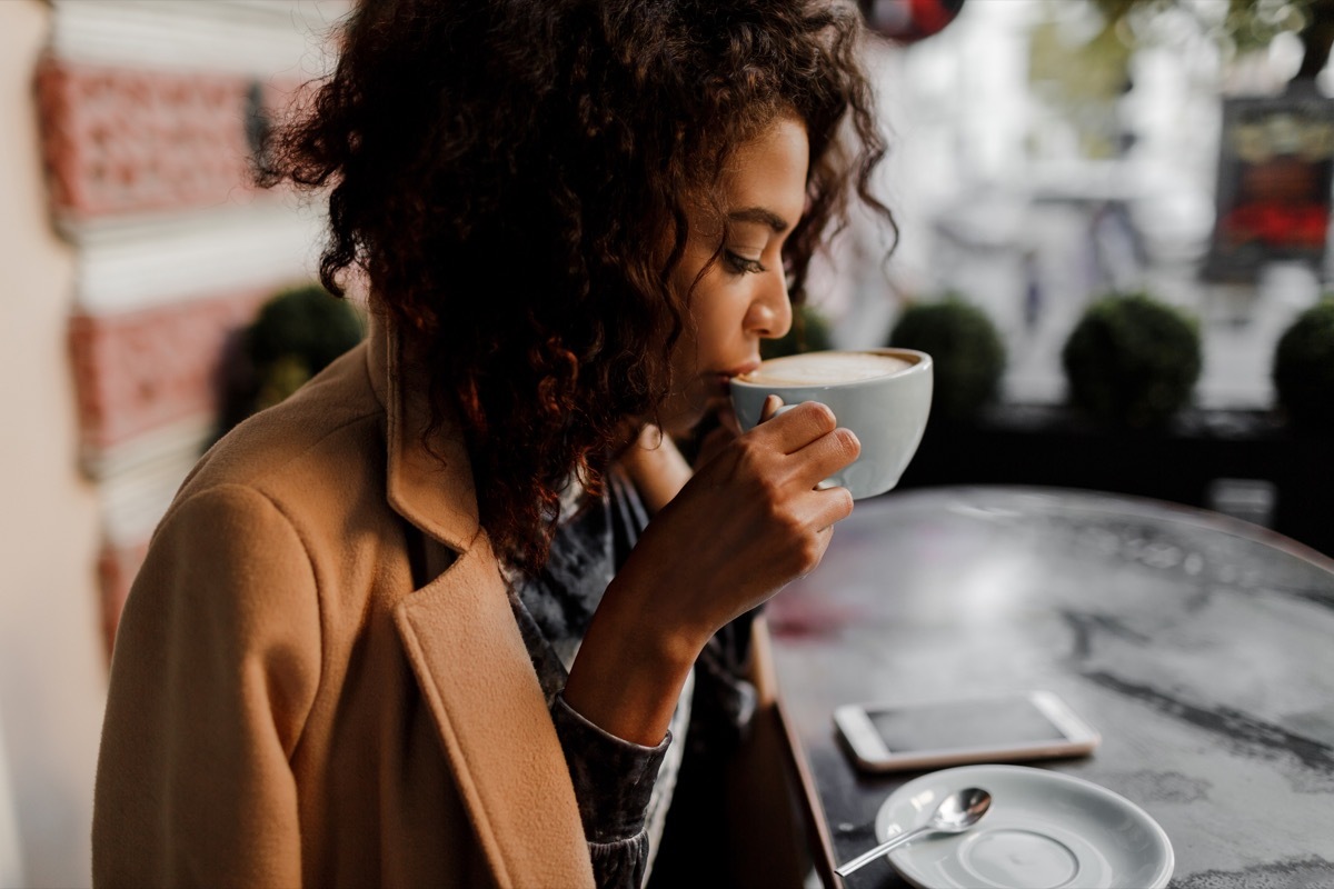 Black woman drinking a latte in a coffee shop in the winter