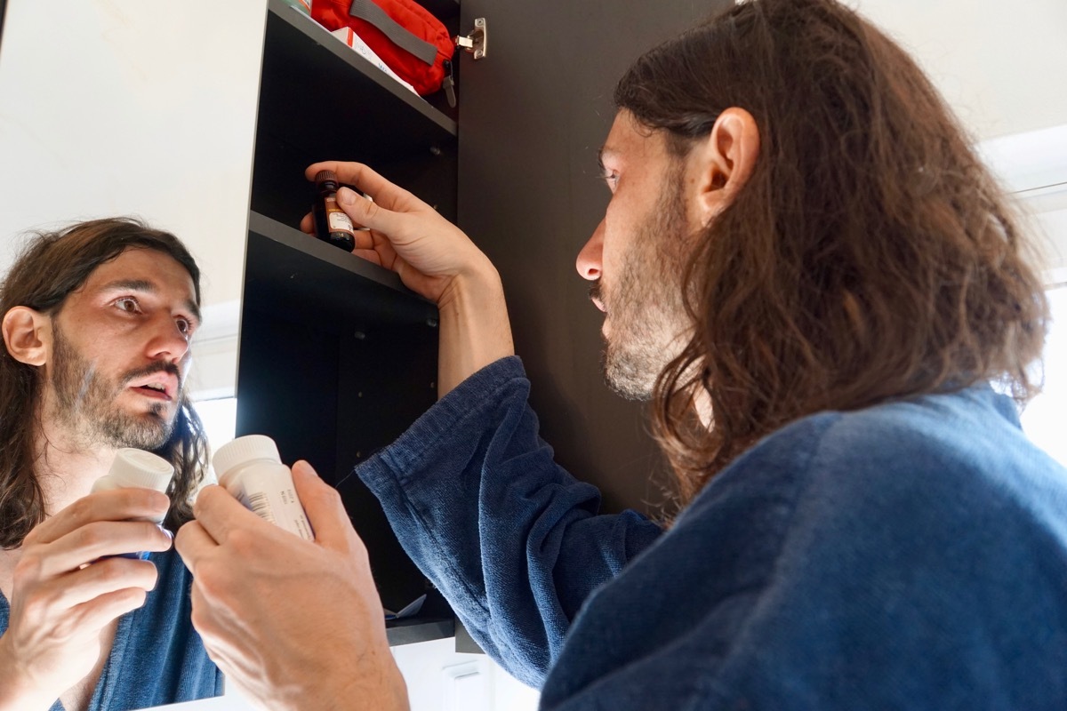 man looking in medicine cabinet