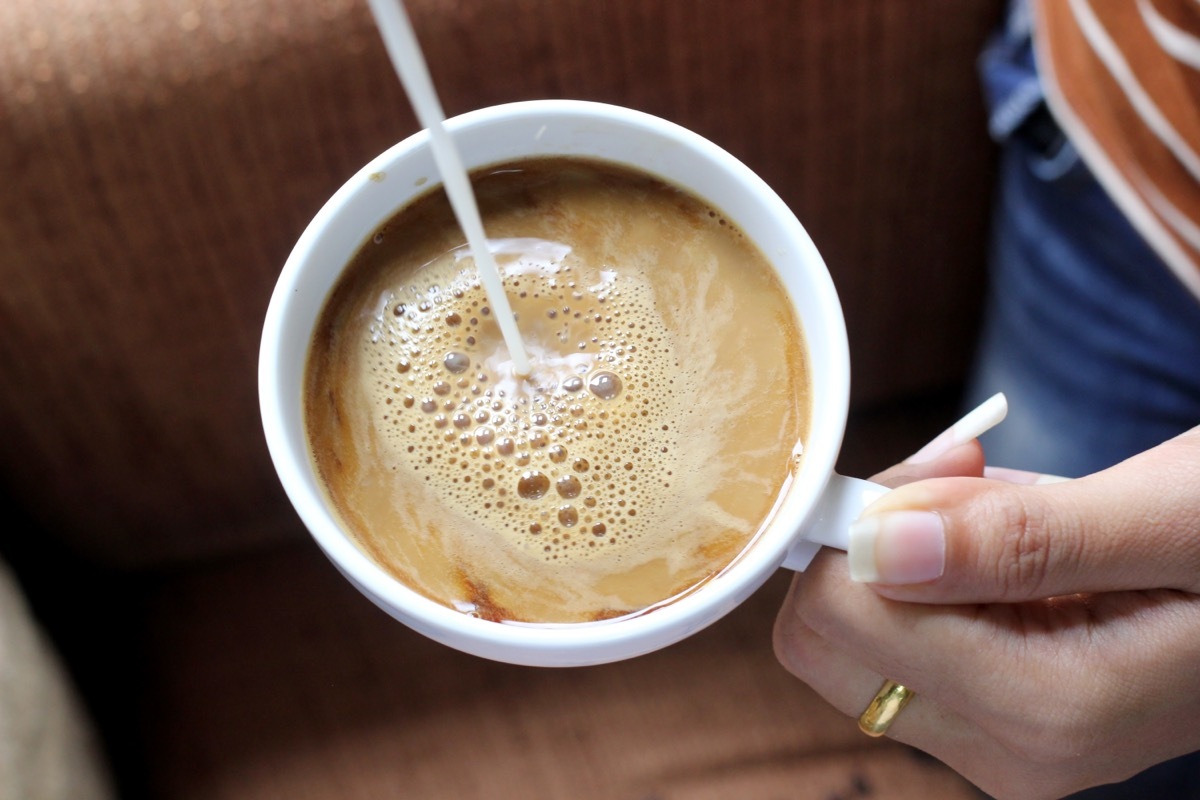 pouring creamer into coffee