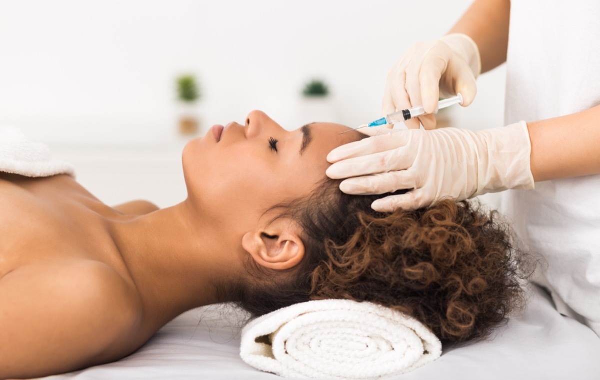 woman laying down on a spa bed getting an injection in her forehead