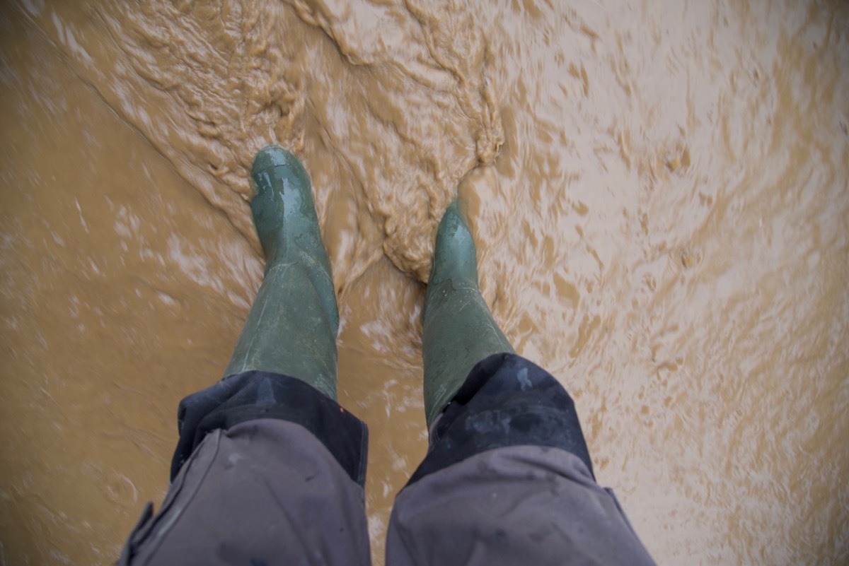 person wearing green boots in flood water