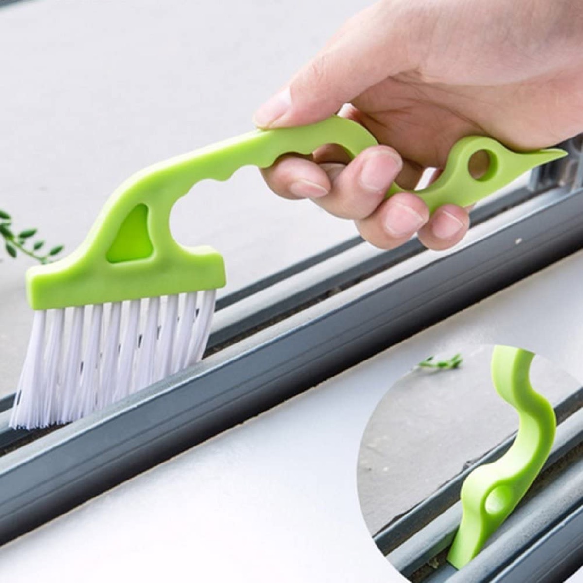 white hand cleaning window gap with green brush