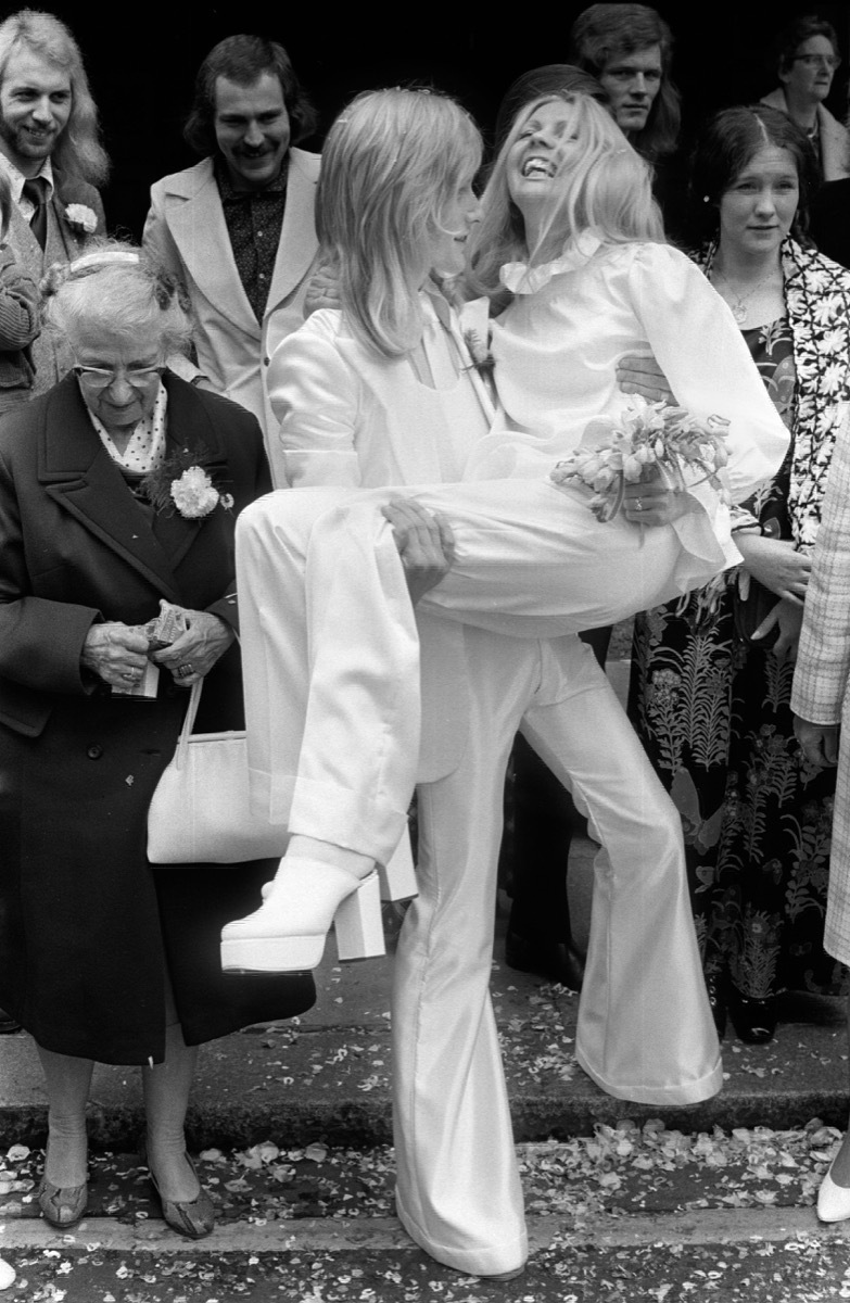 Stylish wedding couple wearing unisex matching trouser suits his and hers in 1970s