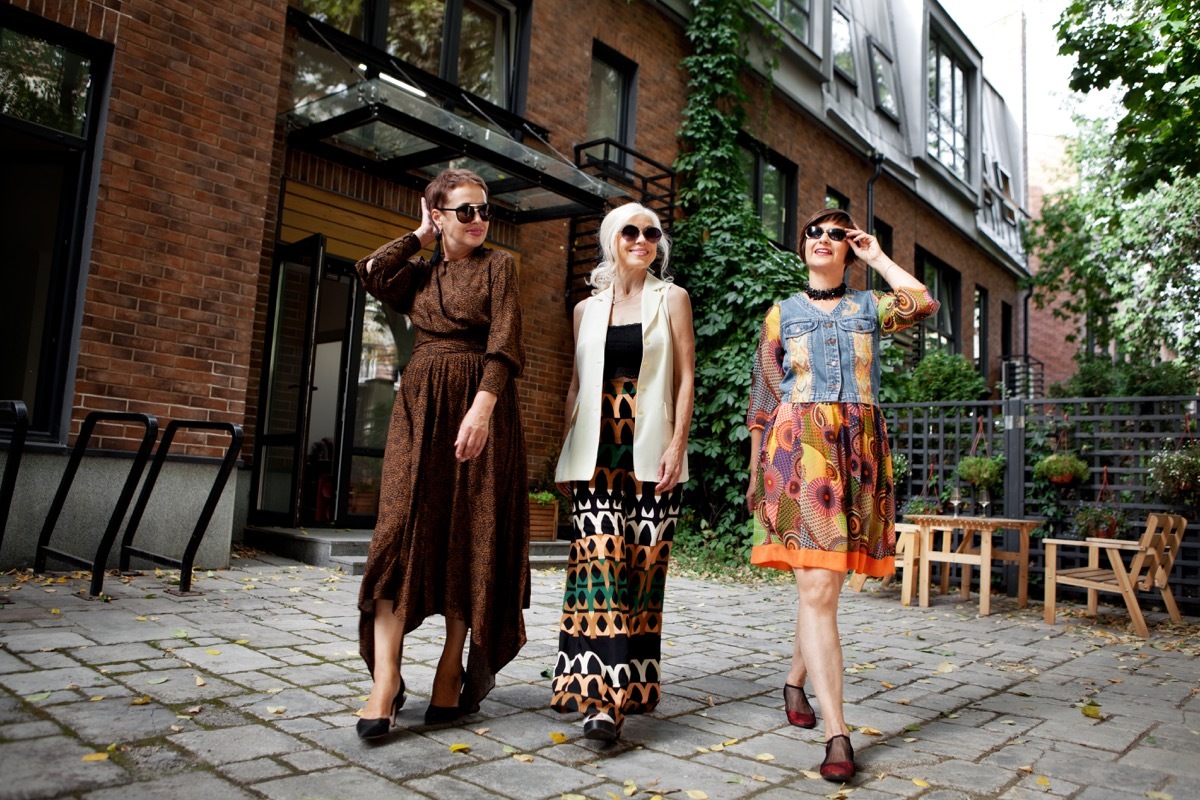 Group of full length elderly women having fun walking city street, three retired female friends, happy mature woman outdoors