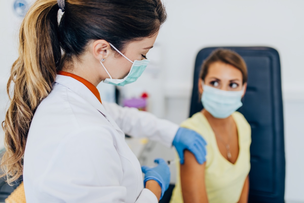 Female doctor or nurse giving shot or vaccine to a patient's shoulder