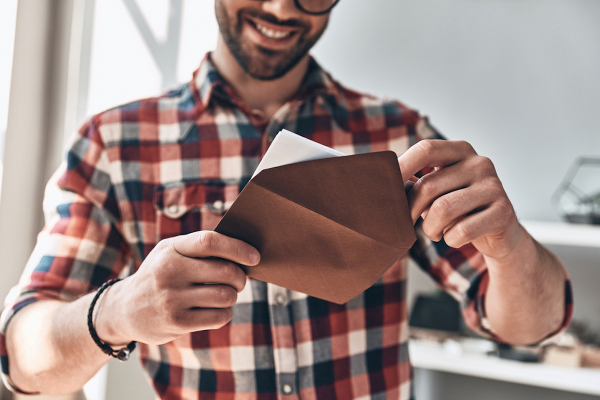 closeup of man putting greeting card in envelope and smiling