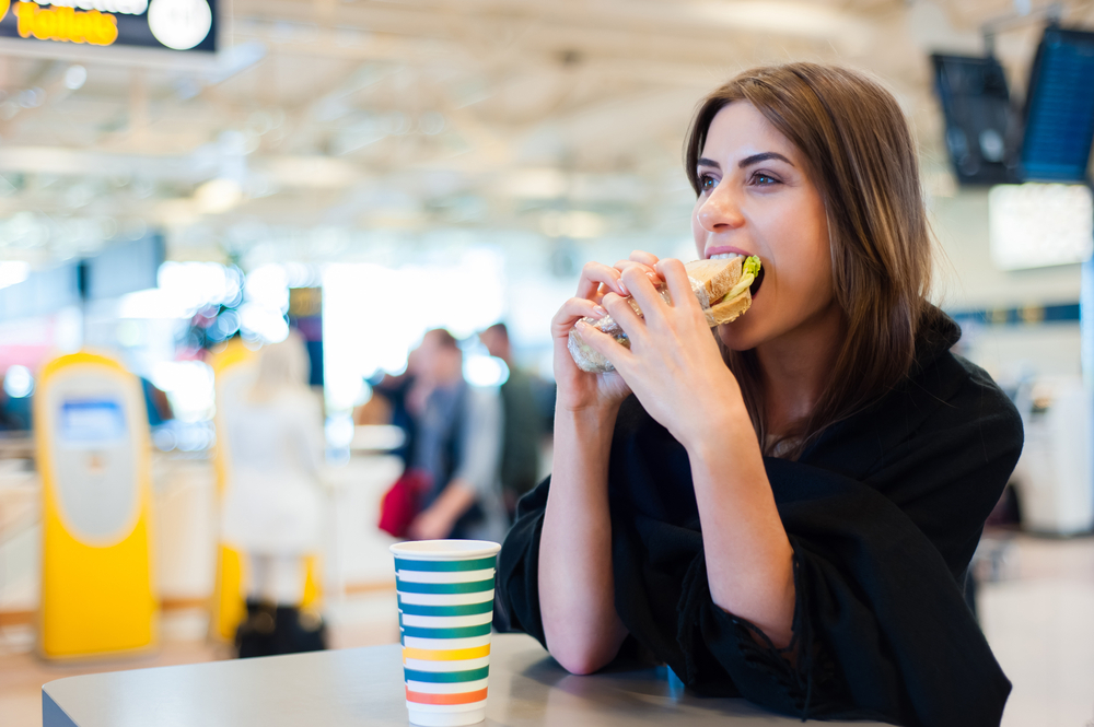 A young woman eating a sandwich in the airport