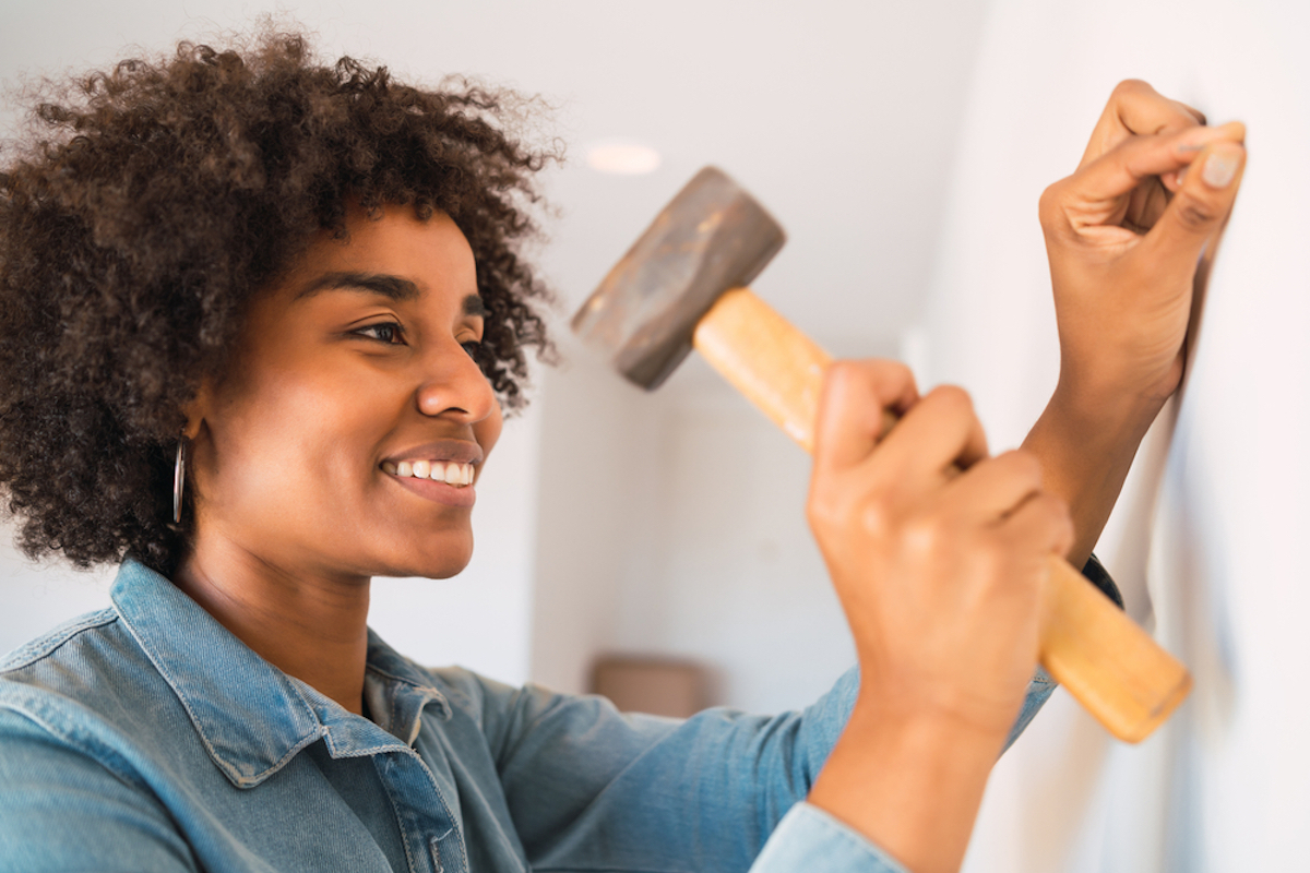 young woman hammering nail into wall