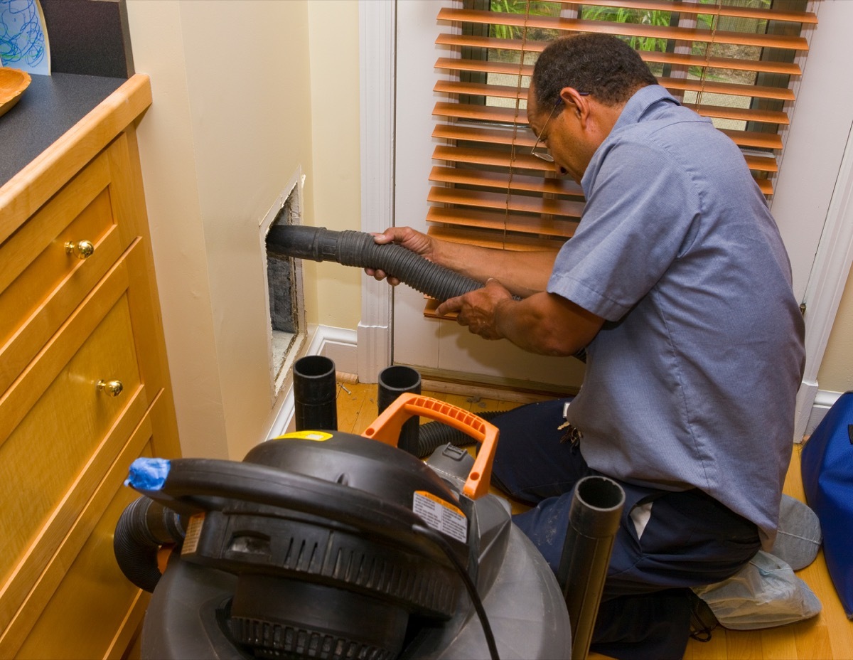 man cleaning air duct in a kitchen