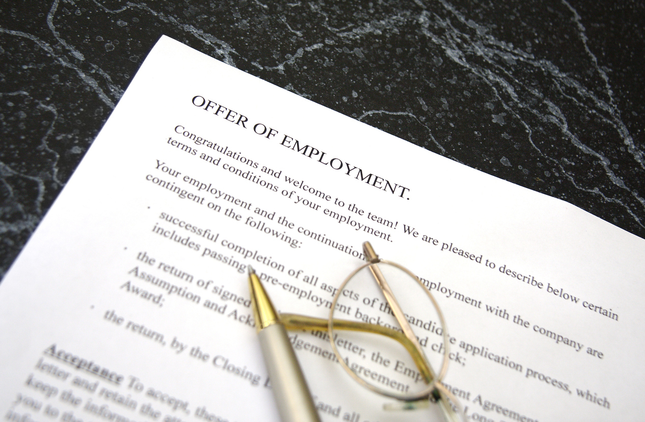 A close up of an offer of employment document with gold glasses sitting on top